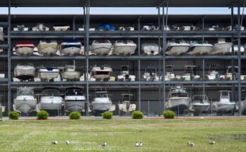 A large, open steel structure contains three shelf levels. Boats of different sizes and types sit on the various shelves.