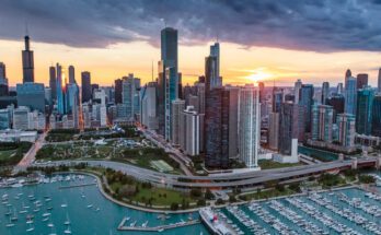 The Chicago skyline during sunset. Below the tall buildings is Lake Shore Drive and the lake with boats moving around.