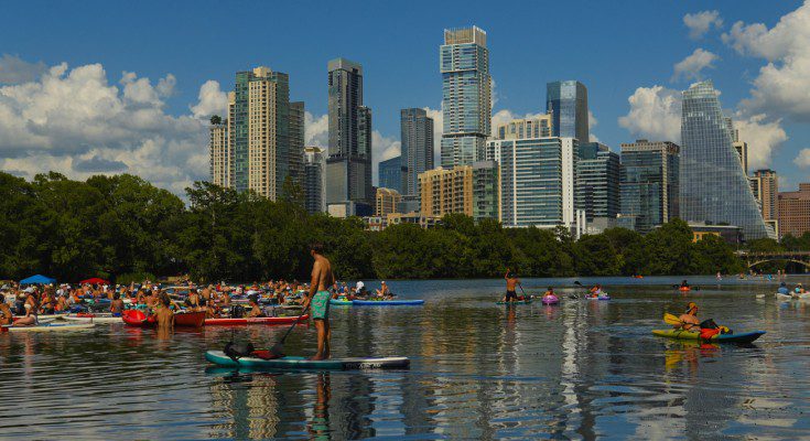 A group of kayakers, canoers, and paddleboarders congregates on the water at Lady Bird Lake in Austin, Texas.