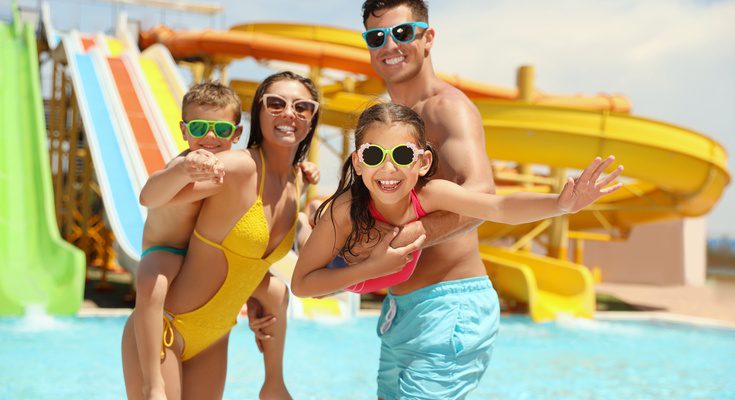 A mom, dad, toddler-aged son, and an elementary school-aged daughter are in bathing suits at a waterpark.